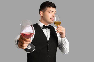 Gri arka planda şarap kadehleri olan genç şarap garsonu.
