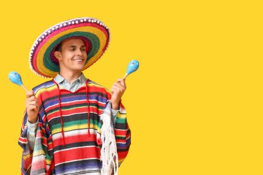Sarı arka planda marakas olan sombrero 'lu yakışıklı bir genç.