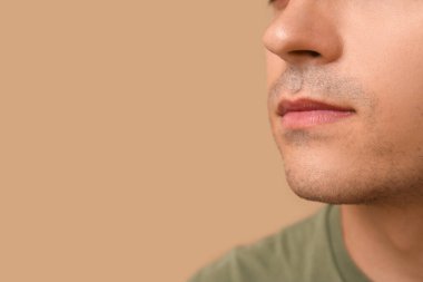 Kahverengi arka plandaki hasta genç adam, yakın plan.