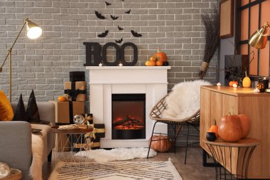 İçinde şömine, koltuk ve Cadılar Bayramı süslemeleri olan festival salonu.