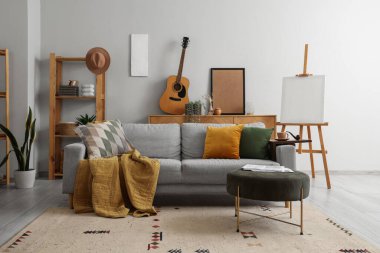 Gri kanepe, sehpa, sehpa ve akustik gitarlı modern oturma odasının içi.