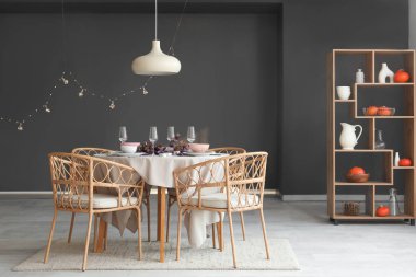 Modern yemek odasında okaliptüs dalları ve yanan mumlarla sonbahar sofrası.