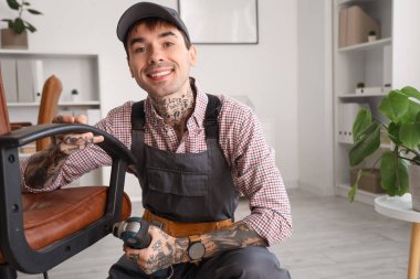 Ofisinde matkap montajı yapan erkek işçi.