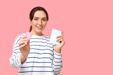 Pembe arka planda regl fincanı ve yastığı olan güzel genç bir kadın.