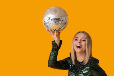 Sarı arka planda disko topu olan güzel genç bir kadın.