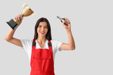 Altın bardaklı ve arka planda kerpeten olan kadın işçi.