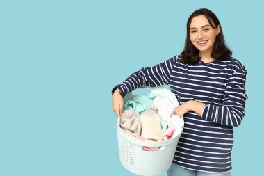 Mavi arka planda çamaşır sepeti olan genç bir kadın.