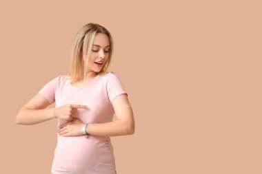 Bej arkaplandaki aşıdan sonra hamile bir kadın.