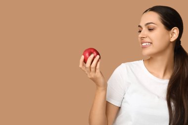 Bej arka planda taze kırmızı elmalı güzel bir kadın.