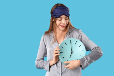 Mavi arka planda saati olan pijamalı güzel bir kadının portresi.