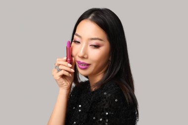 Gri arkaplanda ruj izi olan güzel bir Asyalı kadın.