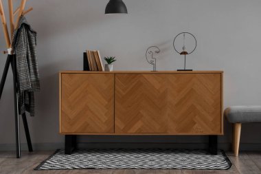 Gri duvarın yanında sıralı ahşap dolap ve halı.