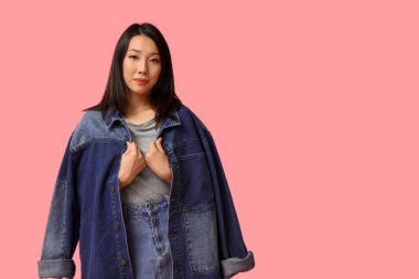 Pembe arka planda şık kot elbiseli güzel bir Asyalı kadın.