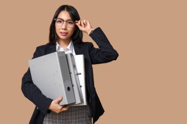 Bej arkaplanda ofis dosyaları olan Asyalı genç iş kadını portresi