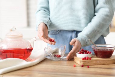 Genç bayan mutfakta yabanmersinli çay yapıyor.