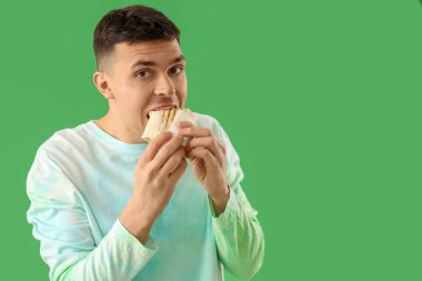 Yakışıklı genç adam yeşil arka planda lezzetli donör kebabı yiyor.