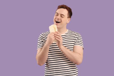 Genç adam mor arka planda donör kebabı yiyor.