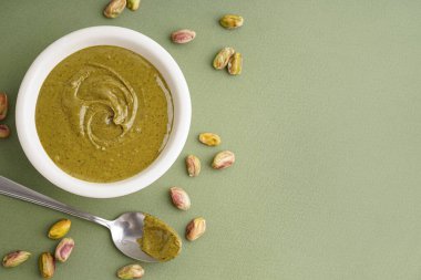 Fıstık ezmeli kase ve yeşil arka planda kaşık.