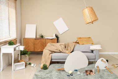 Kanepe, masa ve bitkilerle dolu dağınık bir oturma odası.