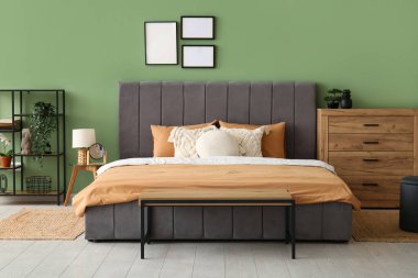 Rahat yatak, yastıklar ve şık yatak odasında ahşap çekmeceler.