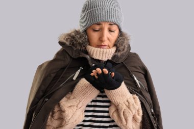 Mature homeless woman with coins on light background, closeup clipart