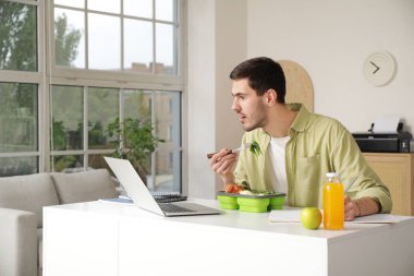 Genç adam ofiste öğle yemeği yiyor.