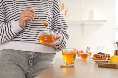 Tatlı ballı genç kadın ve mutfakta bir fincan çay.