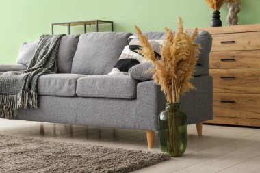 Oturma odasındaki kanepenin yanında kuru kamışlı vazo.