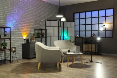 Podcaster 'ın iş yeri, raf üniteleri ve parlayan lambaları olan karanlık stüdyonun içi.