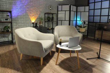 Podcaster 'ın iş yeri, raf üniteleri ve parlayan lambaları olan karanlık stüdyonun içi.