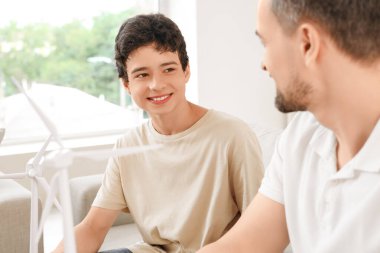 Ergen çocuk ve babasının evde rüzgar türbini modelleri var.