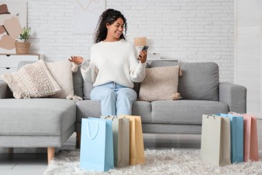 Alışveriş çantaları ve cep telefonuyla mutlu bir Afro-Amerikalı kadın.