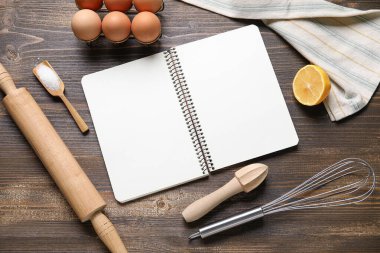 Boş yemek tarifi kitabı, mutfak gereçleri ve ahşap arka planda malzemeler içeren kompozisyon