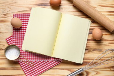 Boş yemek tarifi kitabı, mutfak gereçleri, un ve yumurtalı ahşap zemin.