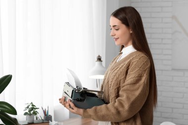 Evinde daktilosu olan güzel, mutlu kadın yazar.