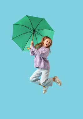 Mavi arka planda yeşil şemsiyeli atlayan genç kız.