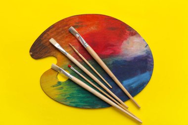 Sarı arkaplanda sanatçı fırçaları ve paletleri