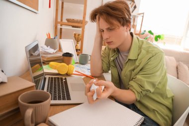 Stresli erkek öğrenci masadaki kağıt kırıntıları.