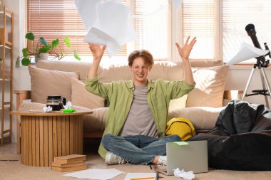 Stresli erkek öğrenci eve kağıt atıyor.