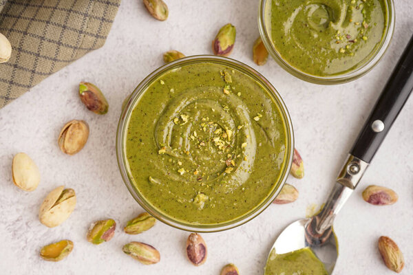 Вкусная фисташковая паста в мисках с ложкой и салфеткой на белом фоне