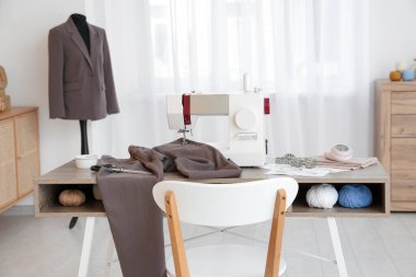 Terzinin dikiş makinesi, farklı malzemeler ve atölye mankeni.