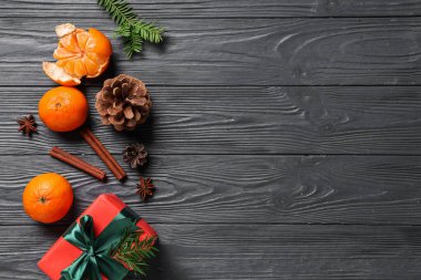 Tatlı mandallı hediye kutusu, gri ahşap arka planda köknar dalları ve koniler.