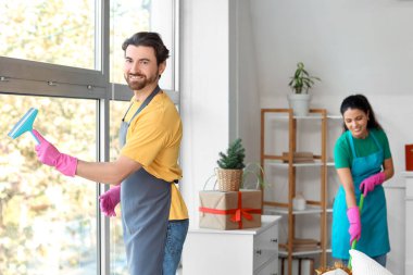 Yeni yıl partisinden sonra odanın penceresini temizleyen erkek hademe.