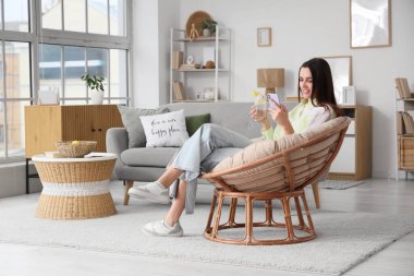 Limonlu su ve cep telefonlu güzel bir kadın evdeki koltukta oturuyor.