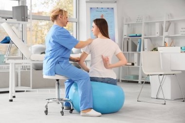 Olgun kadın osteopat klinikte genç bir kadınla çalışıyor.