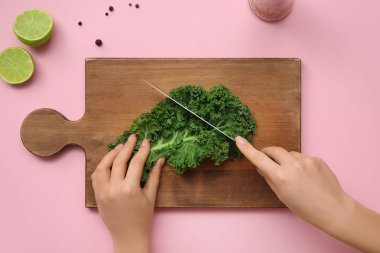 Pembe arka planda lahana yaprağı kesen kadın.