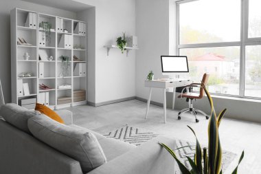 İş yeri, kanepe ve raf ünitesi olan giyim mağazasının içi.