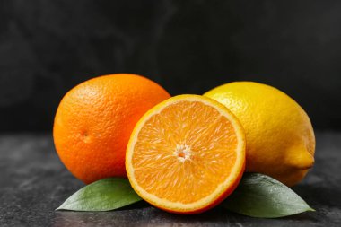 Taze olgun portakallar ve siyah arka planda limon.