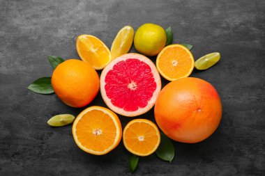 Farklı turunçgil meyveleri ve siyah arkaplanda yapraklar