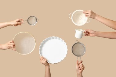 Süt testisi, fırın kabı ve bej arka planda kevgir tutan kadın elleri